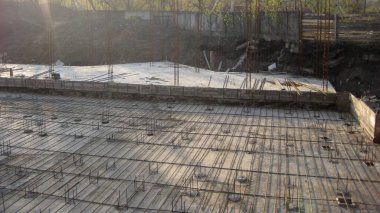 Düşük açı, güneşli bir günde beton dökülmeye hazır beton ve ahşap çerçeveli bir temel inşa etmenin ilk aşamalarını gösteriyor..