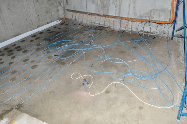 Beton bir odada, mavi borularla döşenmiş, beton döşenmiş, mavi borular döşenmiş, doldurulmaya hazır..