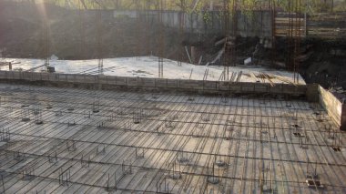 Düşük açı, güneşli bir günde beton dökülmeye hazır beton ve ahşap çerçeveli bir temel inşa etmenin ilk aşamalarını gösteriyor..