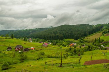 Ukrayna 'daki Karpat Dağları' ndaki küçük bir köyün manzarası bulutlu bir gökyüzünün altında, seyahat ve doğa temaları için mükemmel..
