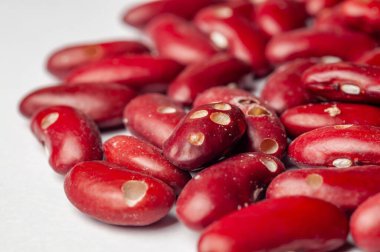 Kırmızı fasulye yığınının makro çekimi, canlı renklerini ve doğal dokusunu beyaz arka planda sergiliyor..