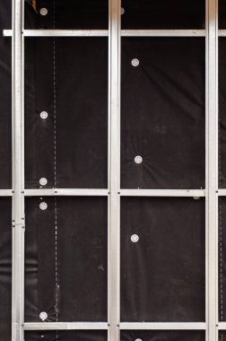 İnşaat halindeki bir binanın yakın çekimleri, beyaz bağlayıcılar ve metal bir iskelet tarafından tutulan siyah tabakayı ortaya çıkardı..