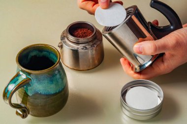 Kahve demlemek için bir Moka demliği hazırlıyorum, filtre yerleştiriliyor ve seramik bardak doldurulmayı bekliyor..