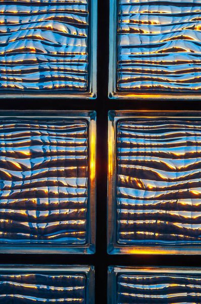 Вид солнечного света, отражающегося через текстурированные стеклянные блоки, создавая уникальные и современные архитектурные детали.