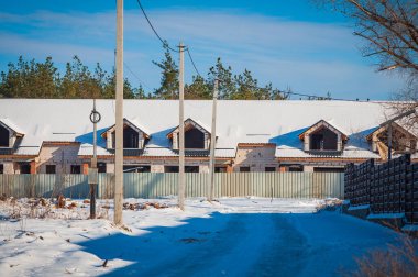 Kış mevsiminde inşaat halindeki, üzerinde mavi gökyüzü olan bir dizi kasaba evinin dış görünüşü..