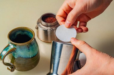 Tarafsız bir yüzeyde, el yapımı seramik bardakla birlikte kağıt filtreli bir kahve makinesini hazırlarken görüldü..