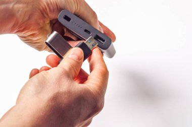Eller bir USB flaş belleği gri bir güç bankasına temiz beyaz bir arka plana bağlıyor. Veri depolama ve taşınabilir şarj çözümleri için ideal.