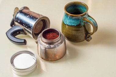 Parçalanmış bir soba espresso makinesi filtrelerinin yanında duruyor ve bir fincan koyu espresso demlemeye hazır renkli bir kupa..