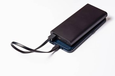 Siyah enerji bankası, taşınabilir enerji çözümlerini yüklemek ve resmetmek için USB kablosu olan bir akıllı telefona bağlıdır.