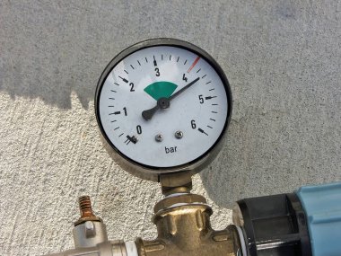 Bir dairesel basınç ölçer yakın çekim göstergesi bir basınç göstergesi, borular üzerine monte, beton üzerinde açık hava, yakalama hassas ölçüm.
