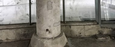 Geniş bir pencereye bitişik, desenli, yıpranmış beton bir sütun kentin manzarasına endüstriyel cazibe katar..
