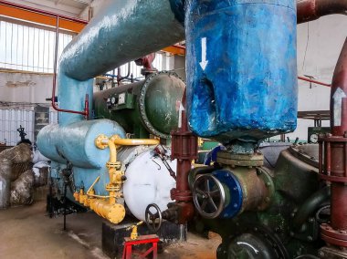 Boruları, vanaları ve aşınma belirtilerini gösteren göstergeleri olan endüstriyel hava sıkıştırma ünitesi işlevsellik ve amaç izlenimi veriyor..