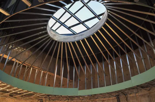 Metal iskelet ve çarpıcı bir oval tavan penceresinin yer aldığı modern bir bina tasarımı, gelişmekte olan mimari tasarımı yakalıyor.