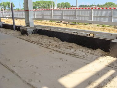 Binanın kenarıyla bariyer arasındaki alanı dolduran kumu gösteren bir inşaat sahasına yakın plan..