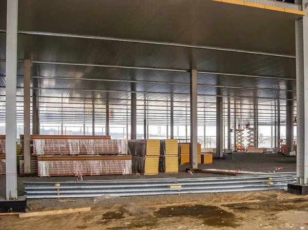 Yeni bir depo inşaatında geniş çelik iskelet içinde yalıtım panelleri ve metal kirişler kurulumu bekliyor..