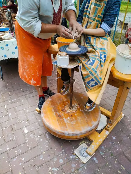 Kyiv, Ukrayna. 10 Aralık 2023. Kil tenceresi yapıyorum. Bir çömlek eğitmeni ve bir öğrenci çömlek çarkında kilden bir çömlek yapıyorlar. Festivaldeki doğal sokak fotoğrafı.