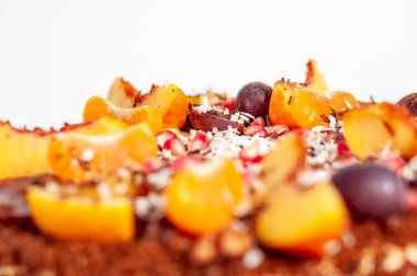 Beyaz arka planda taze meyvelerle süslenmiş canlı ve renkli bir tatlının yakın çekimi. Yemek blogları için mükemmel..