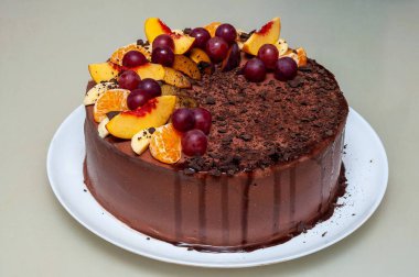 Taze meyvelerle süslenmiş zengin bir çikolatalı pasta beyaz bir tabakta oturur. Tatlı özel durumlar ya da tatlı ikramları için mükemmeldir..