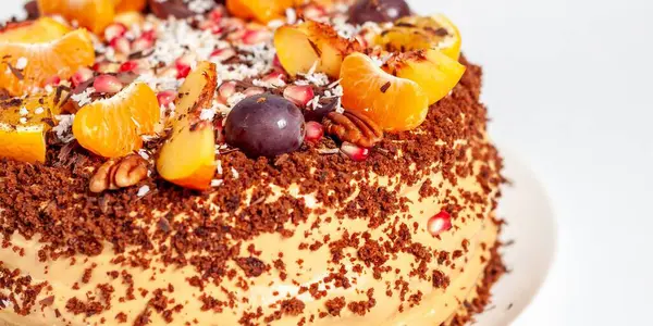 Taze meyve ve fındıkla süslenmiş bu lezzetli görünümlü pasta beyaz bir tabakta servis edilir. Bu tatlı ziyafet kutlamalar için ideal..