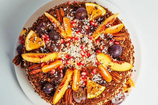 Çeşitli meyveler, fındıklar ve hindistan cevizi taneleriyle süslenmiş güzel bir pasta kutlama için mükemmel bir tatlı oluşturur..