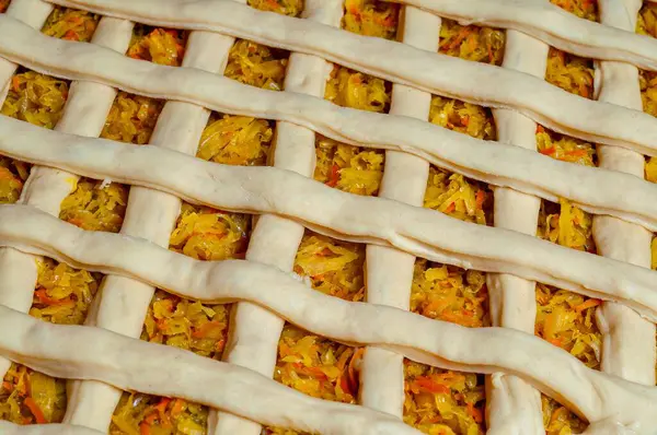 Yakından çekilmiş, lezzetli bir turta kafes kabuğuyla birlikte lezzetli lahana ve havuçla pişirilmeye hazır..