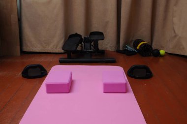 Pembe yoga minderi, egzersiz blokları ve antrenman için hazırlanmış bir spor salonu..
