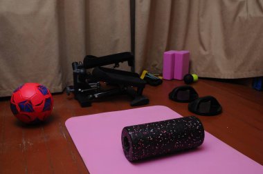 Bir spor salonu düzeneği, ahşap bir zeminde egzersiz için hazır çeşitli ekipmanlara sahiptir. Sahne fitness araçlarına odaklanıyor.
