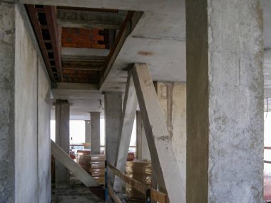 İç perspektifte, inşaat halindeki bir binada işlenmemiş beton sütunlar ve destekler sergileniyor..