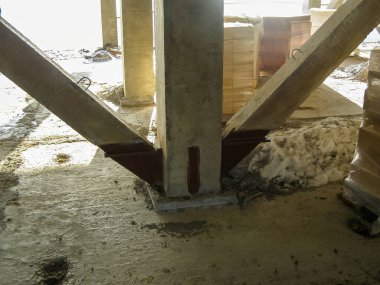 Beton sütunlar ve ahşap kirişler inşaat sırasında bir binanın yapısını destekliyor, mimari ayrıntılar ve malzemeler sergileniyor.