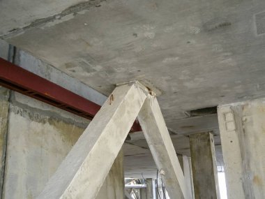 Bir binayı destekleyen beton sütunların ve kirişlerin yer aldığı yapısal bir manzara, inşaat ayrıntılarını gösteriyor.