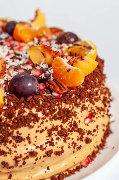 Güzel dekore edilmiş, taze meyve, fındık ve rendelenmiş çikolatayla süslenmiş bir pasta yakalar..