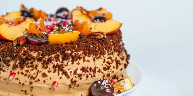 Taze meyvelerle süslenmiş, güzel dekore edilmiş bir pasta, beyaz bir tabağa oturup, kutlamalar için mükemmel bir zemin hazırlar..