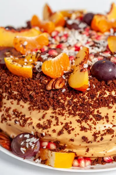 Taze meyve, fındık ve çikolata parçacıklarıyla süslenmiş güzel dekore edilmiş bir pastanın yakın plan görüntüsü. Kutlama için mükemmel..
