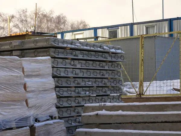 İnşaat elementlerini gösteren beton yığınları bir kış günü bir inşaat sahasında durur..