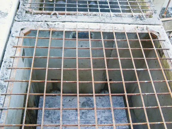 Paslı metal ızgarayla açık bir drenajın yakın plan çekimi altındaki beton yapıyı ortaya çıkarıyor..