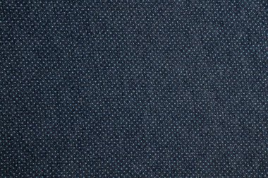 Bu resim, küçük, eşit aralıklı beyaz noktalı koyu mavi bir kumaşın yakın çekimini gösterir ve desenli bir desen yaratır..