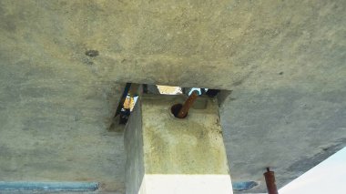 Açık destekli beton bir yapıya, bir levhanın altına bakıyorum. İnşaatın ayrıntıları görünür..