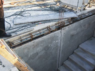 Beton duvarlar, çeliğin güçlendirilmesi ve aşağı inen bazı basamakları olan ahşap destek yapısına sahip inşaat alanı..