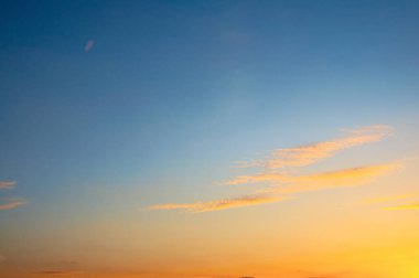 Canlı günbatımı, turuncu, sarı ve mavi tonlarıyla gökyüzünü boyar ve nefes kesici doğal bir görüntü yaratır..