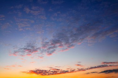 Bulutlu güzel günbatımı gökyüzü, turuncu, sarı, pembe ve mavi gibi canlı renkler sergiliyor. Resimli bir sahne..