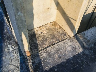 Tepeden çekilen bir çekim beton yapıların keskin açılarını ve aşınmış yüzeyleri yakalar. Kompozisyon, koyu gölgeli bir yakın çekim görüntüsünü ortaya çıkarıyor..