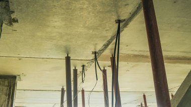 Yukarı bakan yapısal tavan, tamamlanmamış çalışmaları gösteren inşaat alanındaki kirişleri ve kabloları destekliyor..