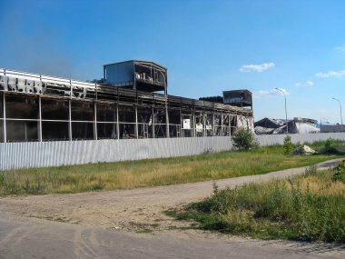 Yangından ağır hasar görmüş, parlak mavi gökyüzüne karşı yanmış kalıntıları olan bir binanın görüntüsü..