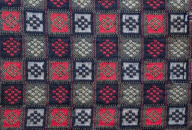 Kırmızı, beyaz ve mavi karelerden oluşan bir kumaşın yakın çekim görüntüsü dokulu ve canlı bir görsel yaratıyor..