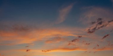 Gün batımında gökyüzü, incecik bulutlarla portakal ve mavinin güzel bir harmanıdır. Huzurlu bir manzara.