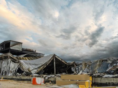 Çökmüş çatıları ve yanmış kalıntıları dramatik, bulutlu bir gökyüzü altında ağır hasar görmüş bir bina..