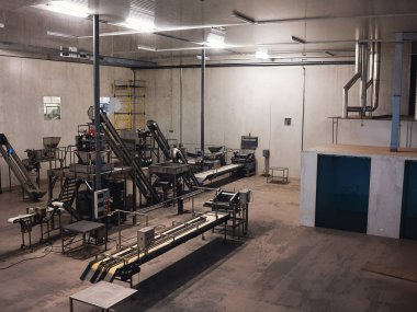 Makineler, taşıma bantları ve endüstriyel ekipmanlarla donatılmış bir fabrika içi çekimin tamamı parlak ışık altında..