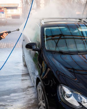Siyah bir araba araba araba yıkamada iyice temizleniyor, yüksek basınçlı su ve sabun köpükleri yaratıyor..