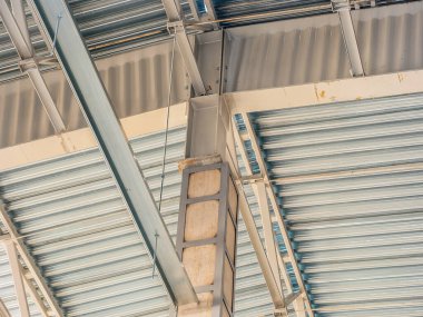 Modern bir binada metal yapı elementlerinin yakın çekimi, kirişler, sütunlar ve kıvrımlı bir tavan.