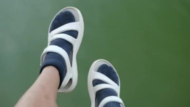 Egzersiz yapan ve ücretini uzatan bir adam mavi çorap ve beyaz ayakkabı giyer..